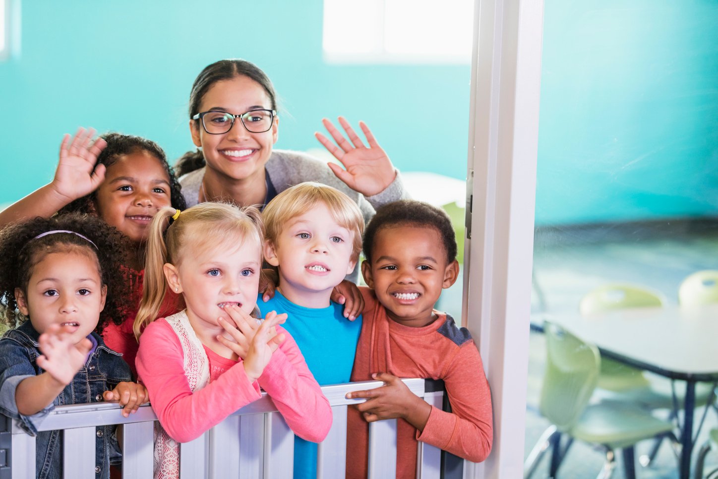 Teacher and preschool students smiling, waving